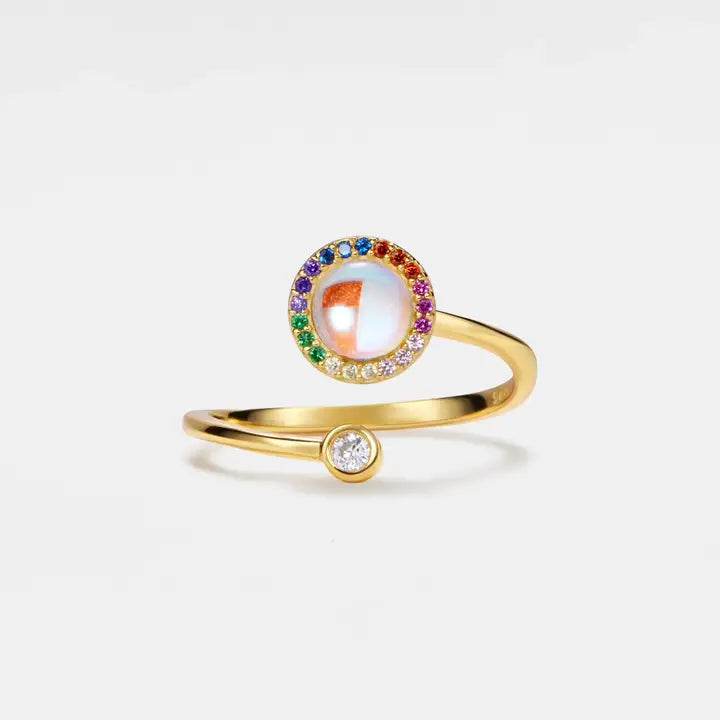 Gold ring with colorful gemstones on a light gray background