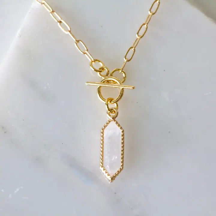 Gold necklace with a clear pendant on a white background