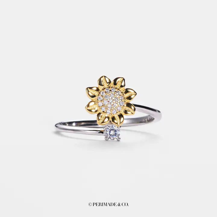 Gold and silver sunflower-shaped ring with diamonds on a white background