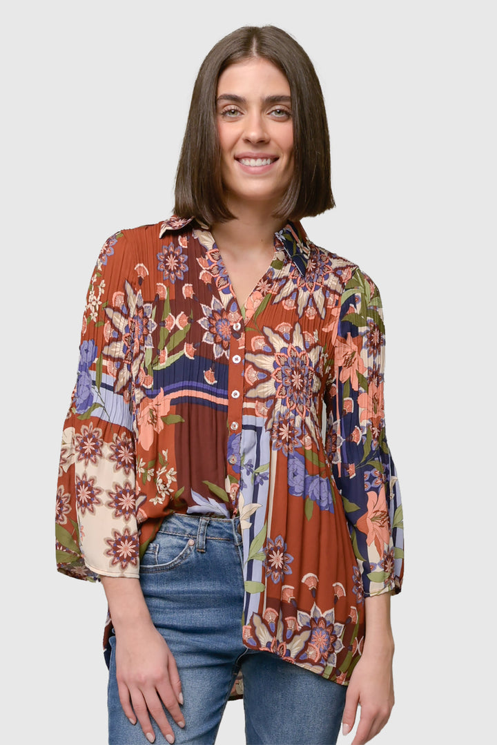 A woman wearing a multicolored floral print bell sleeve blouse with a V-neck and button front.
