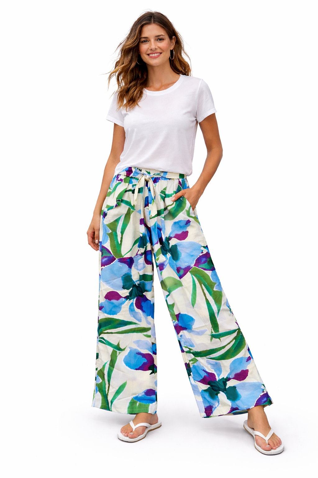 Woman wearing a white t-shirt and colorful floral pants on a white background