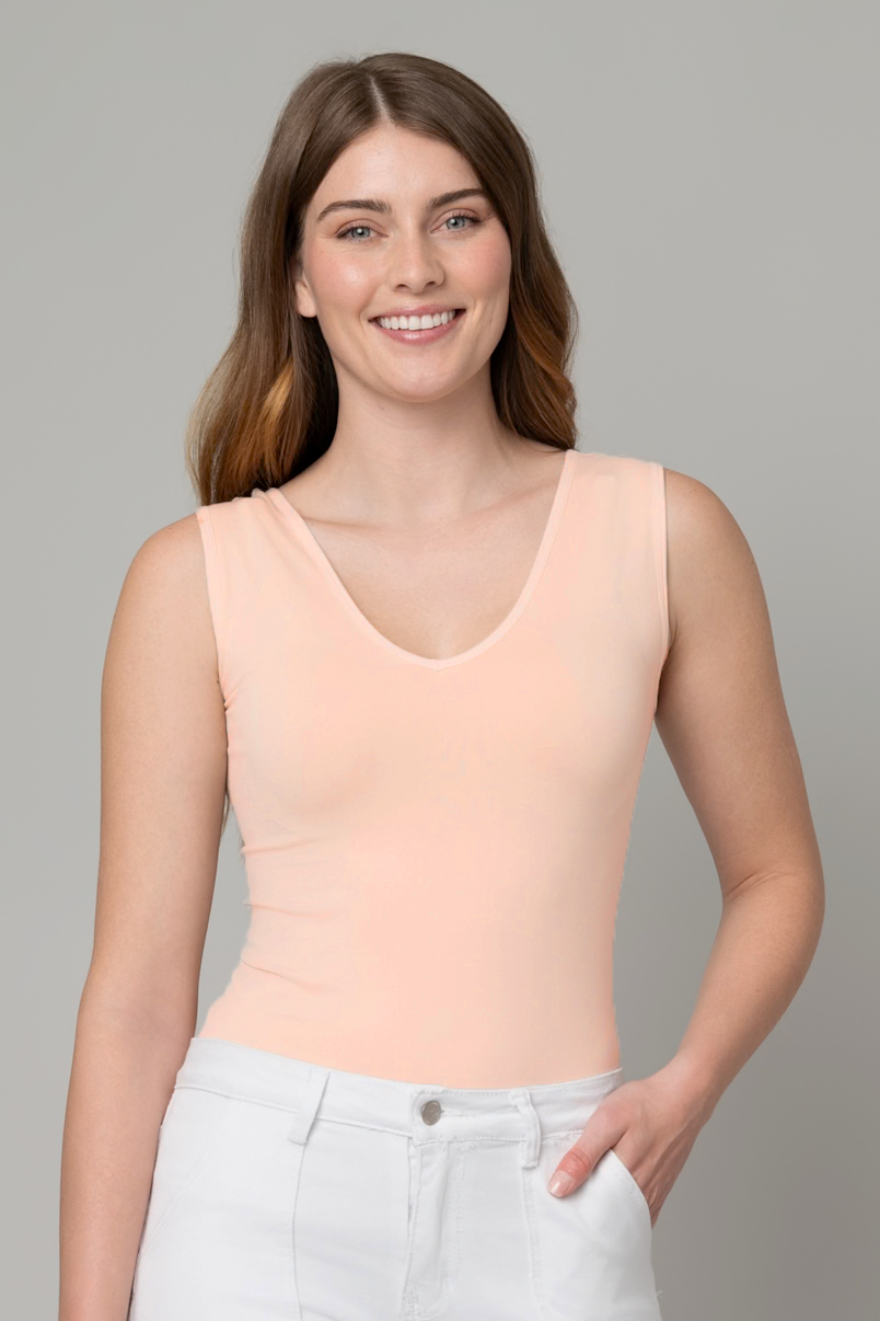 Woman wearing a beige tank top against a gray background