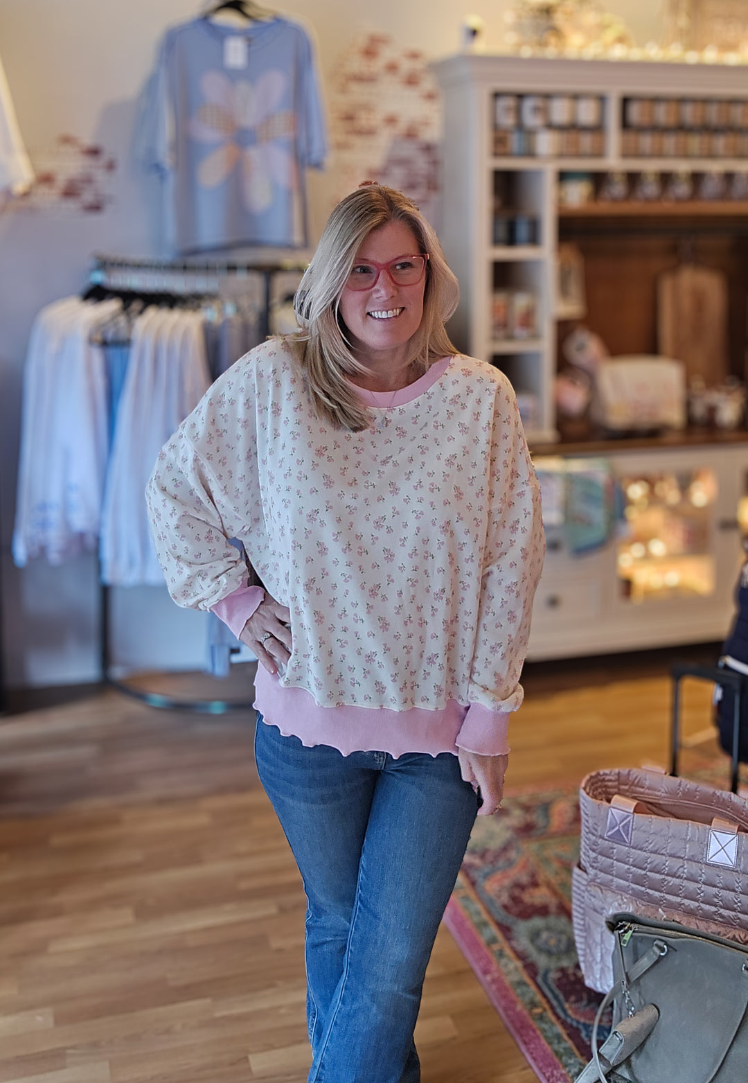 Woman wearing a floral blouse and jeans in a store setting