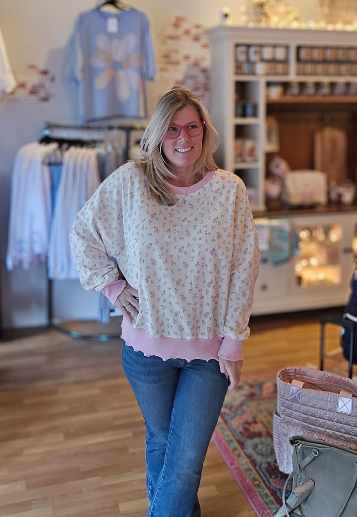 Woman wearing a floral blouse and jeans in a store setting