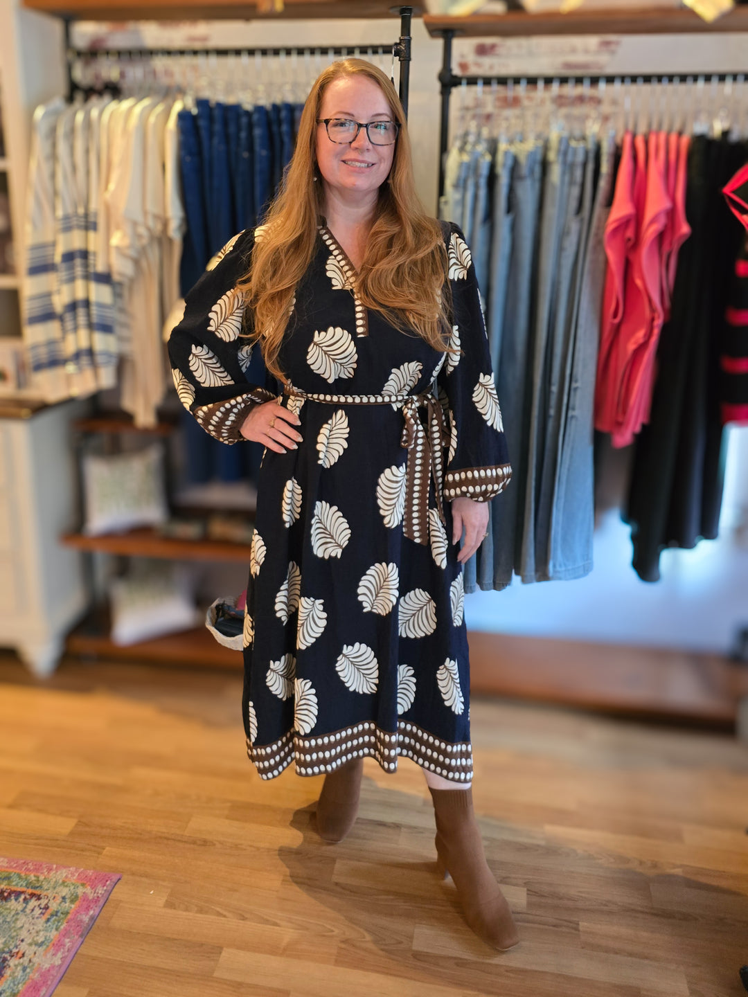 Woman in navy dress with white large leaves wearing brown boots