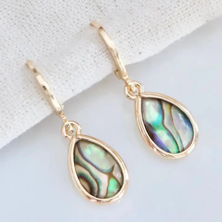 Gold earrings with teardrop-shaped abalone shell stones on a light background