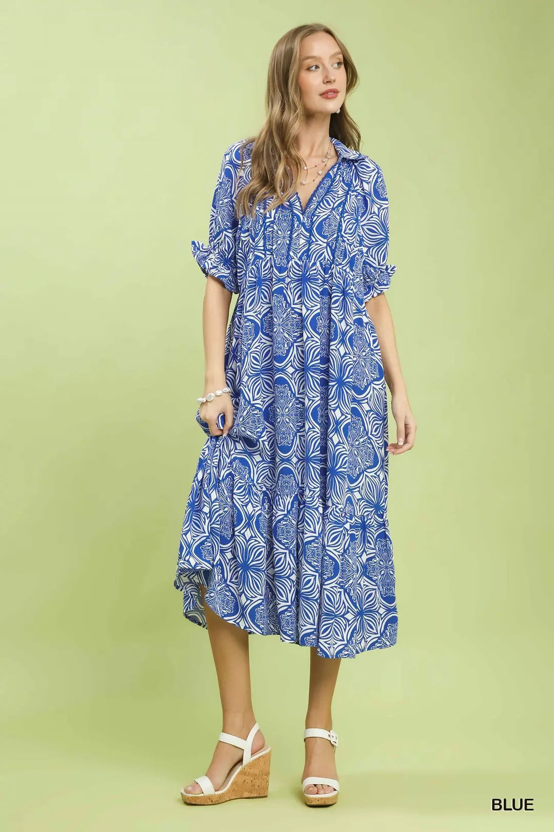 Woman wearing a blue patterned dress on a green background