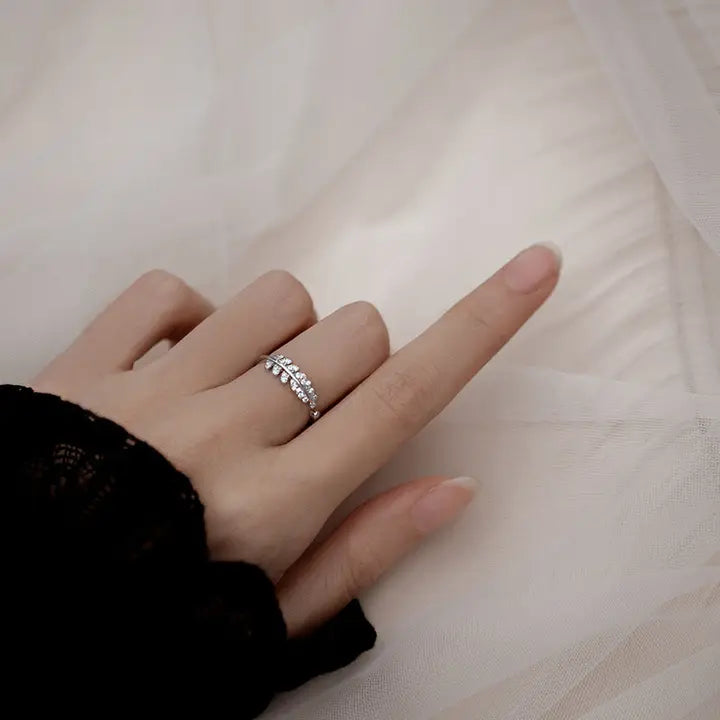 Hand wearing a silver ring on a light fabric background