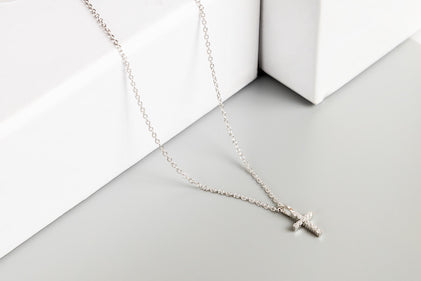 Silver cross necklace on a white surface
