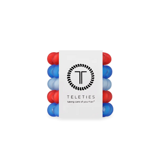 Set of red and blue hair ties with a white label displaying the brand 'Teleties' on a white background.
