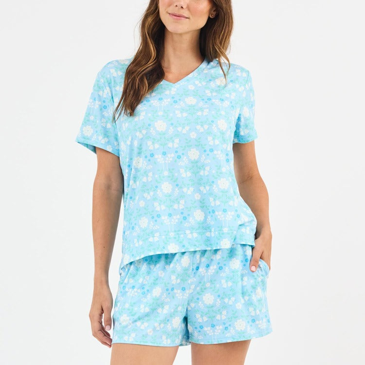 Woman wearing a light blue pajama set with white floral pattern on a white background