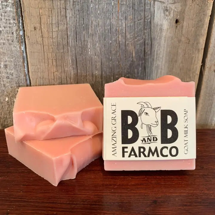 Two bars of pink soap with a B&amp;B Farmco packaging on a wooden surface.
