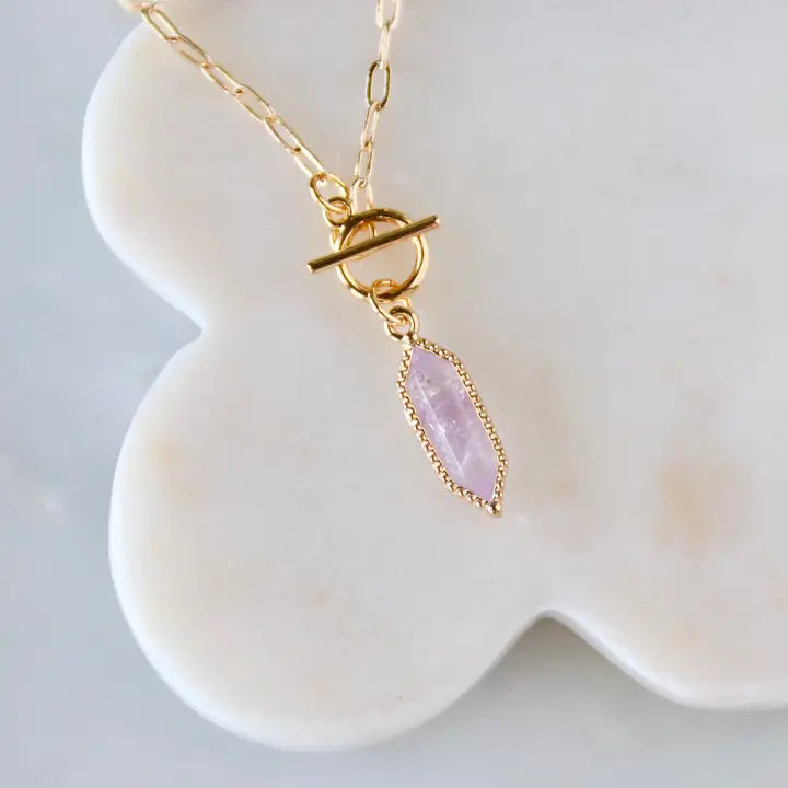 Necklace with a pink stone pendant on a white dish