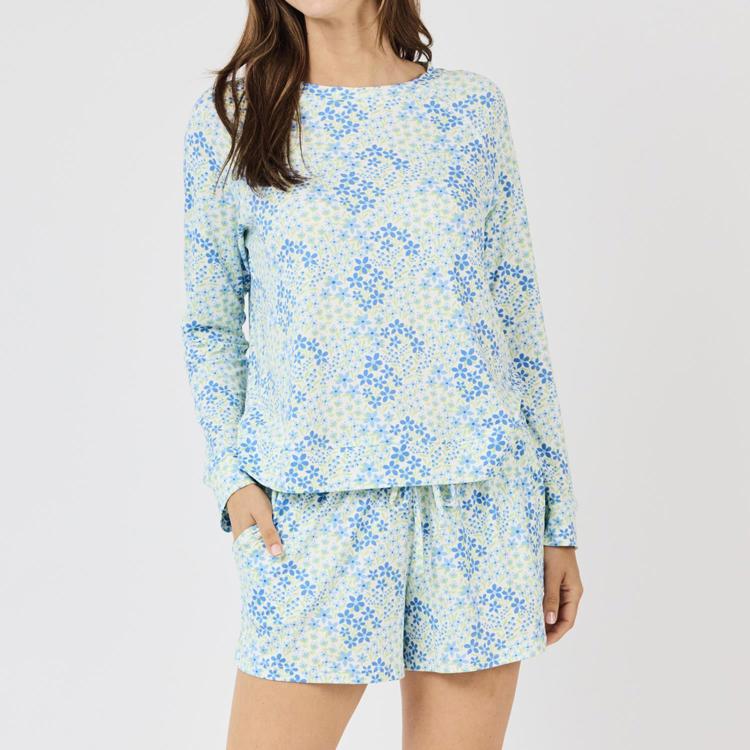 Woman wearing a floral long-sleeve top and shorts set on a plain background