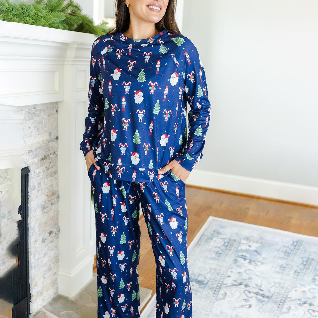 Woman wearing a blue Christmas-themed pajama set in a cozy room.