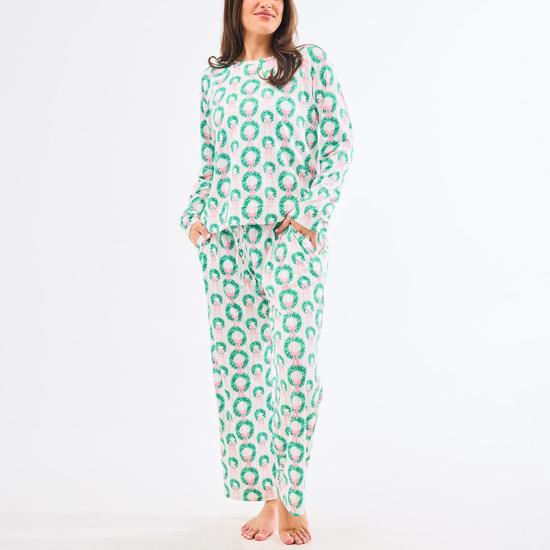 Person wearing a green and pink patterned onesie on a white background