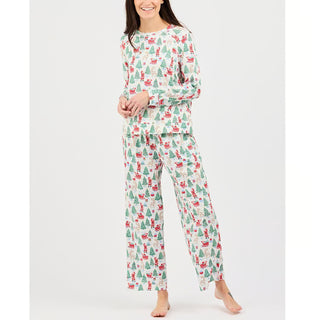 woman wearing pajama set with long sleeve shirt and pants. Design features vintage-inspired santa, christmas tree, reindeer, and sled icons. 