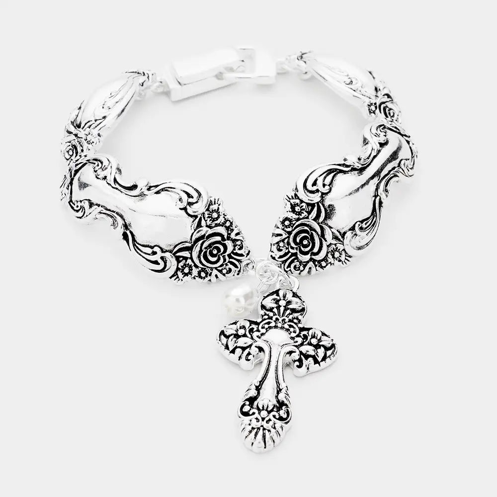 Silver necklace with floral and cross design on a white background