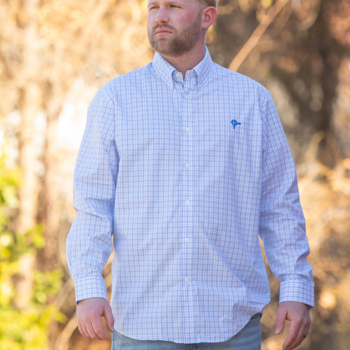Man wearing a light blue checkered shirt with a blurred natural background