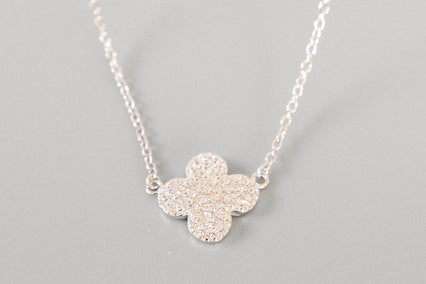 Silver necklace with a flower-shaped pendant on a gray background