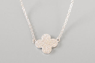Silver necklace with a flower-shaped pendant on a gray background