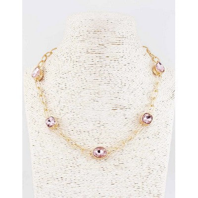 Gold necklace with pink beads on a white stand