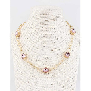 Gold necklace with pink beads on a white stand