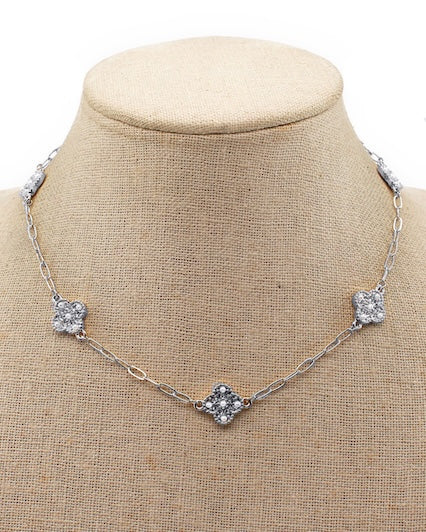 Necklace with square diamond pendants on a beige fabric background