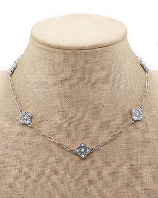 Necklace with square diamond pendants on a beige fabric background