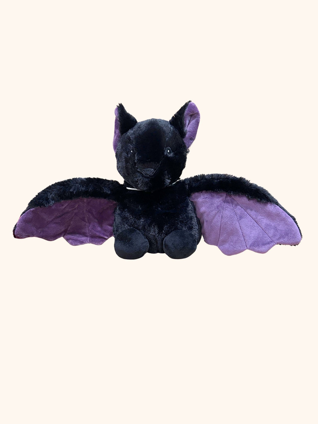 Black plush toy with purple wings on a white background