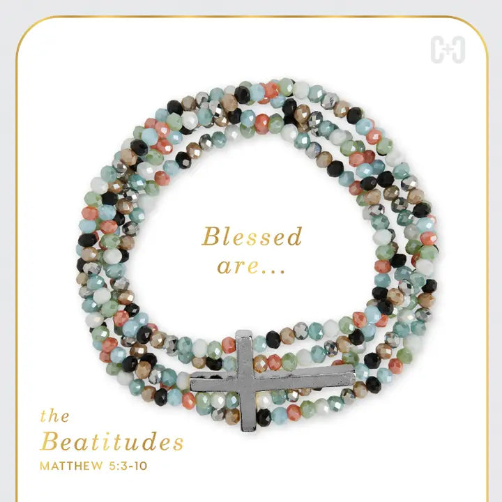Multicolored beaded bracelet with a cross charm on a white background