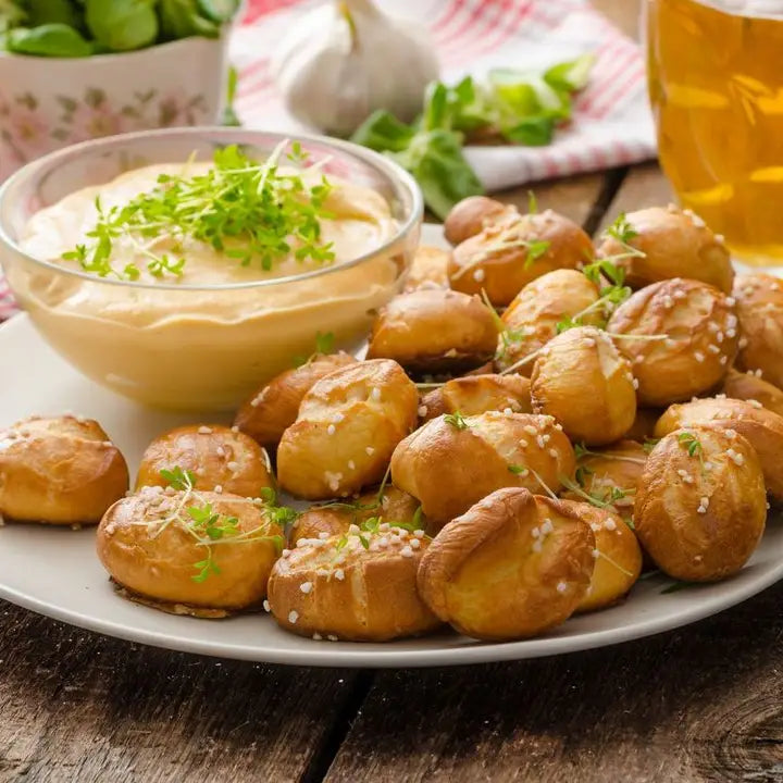 Platter of pretzel bites with a side of dip on a wooden table.