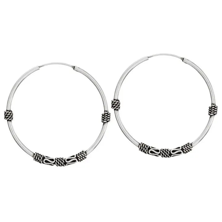 Pair of silver hoop earrings with intricate designs on a white background