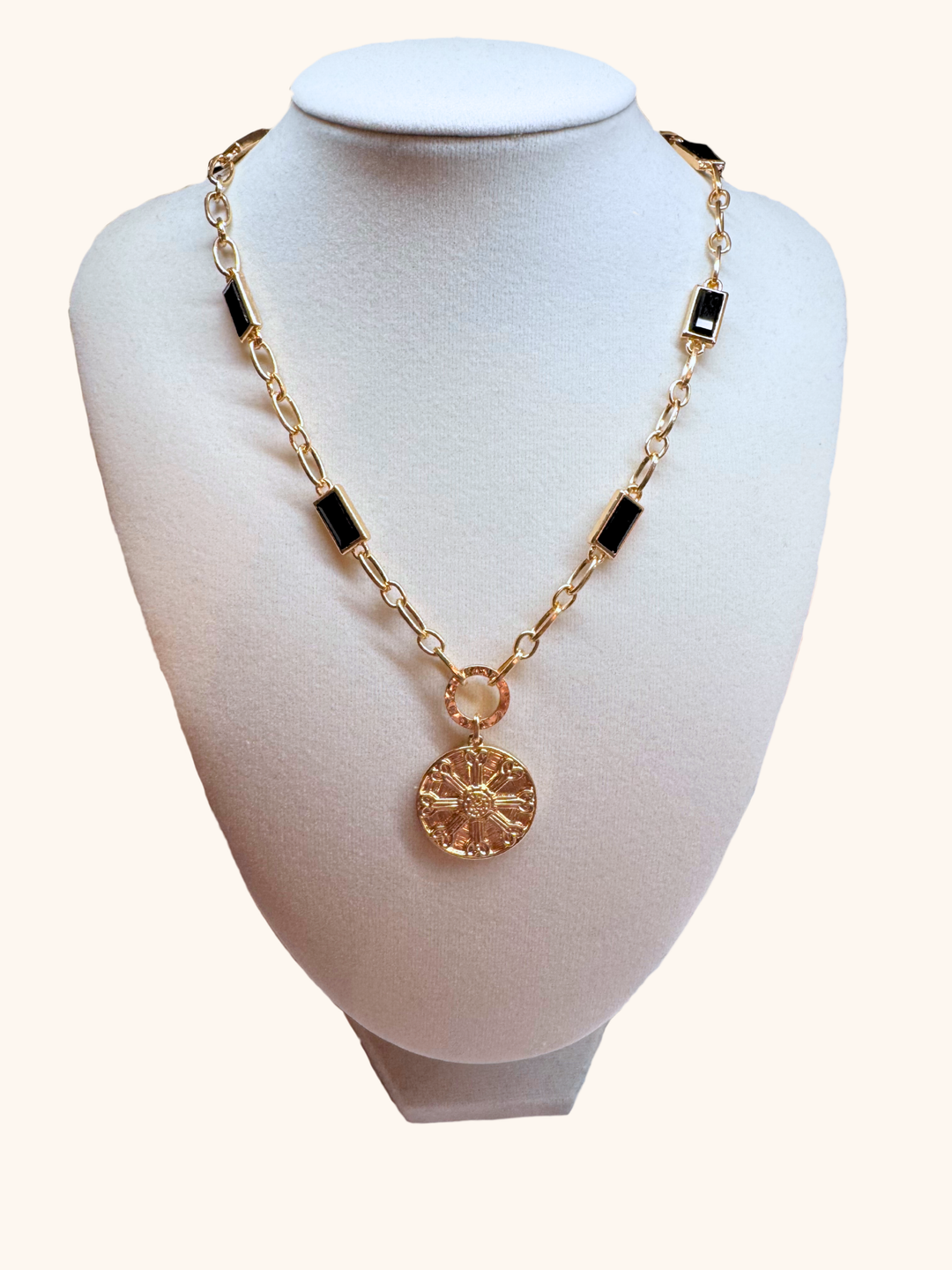 Gold chain necklace with black accents on a mannequin bust.