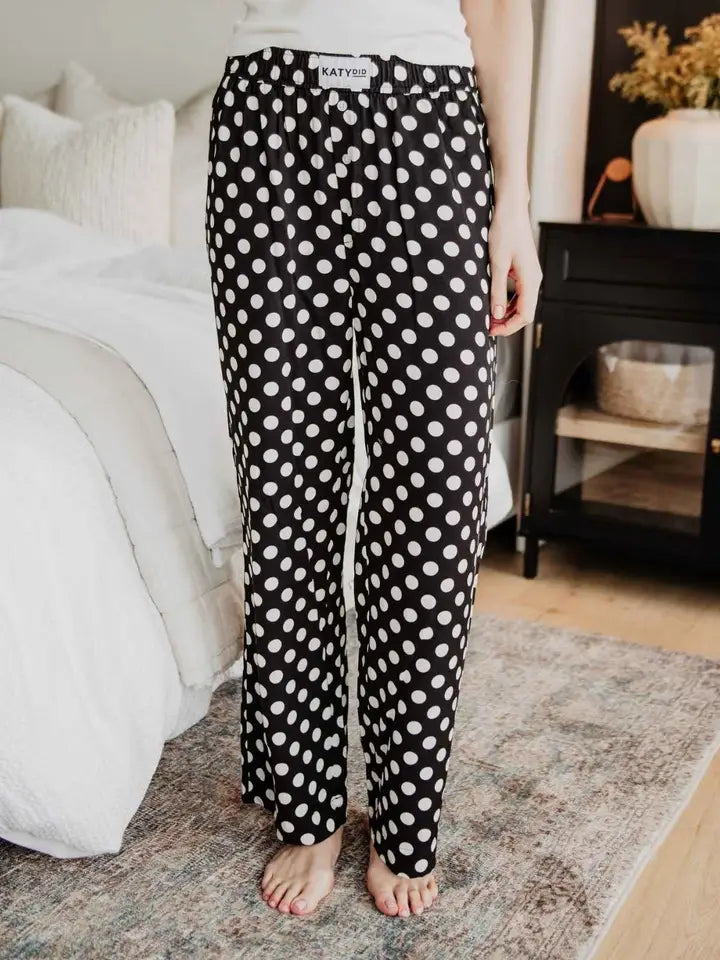 Person wearing black polka dot pajama pants in a bedroom setting
