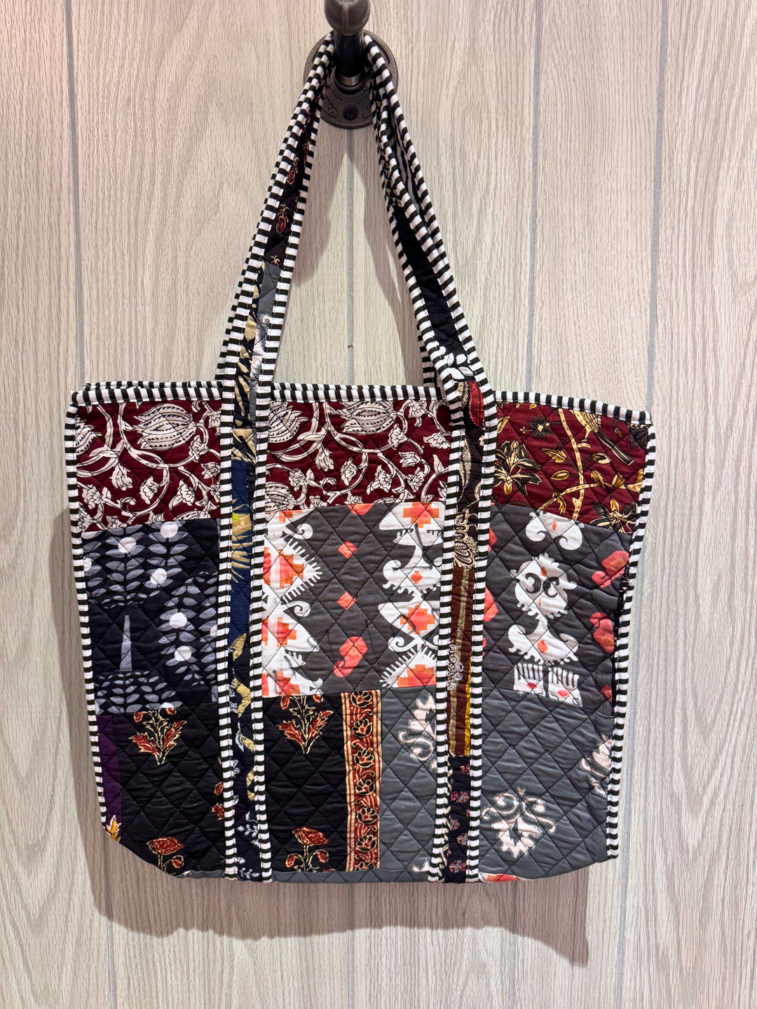 Quilted tote bag with various patterns on a wooden surface