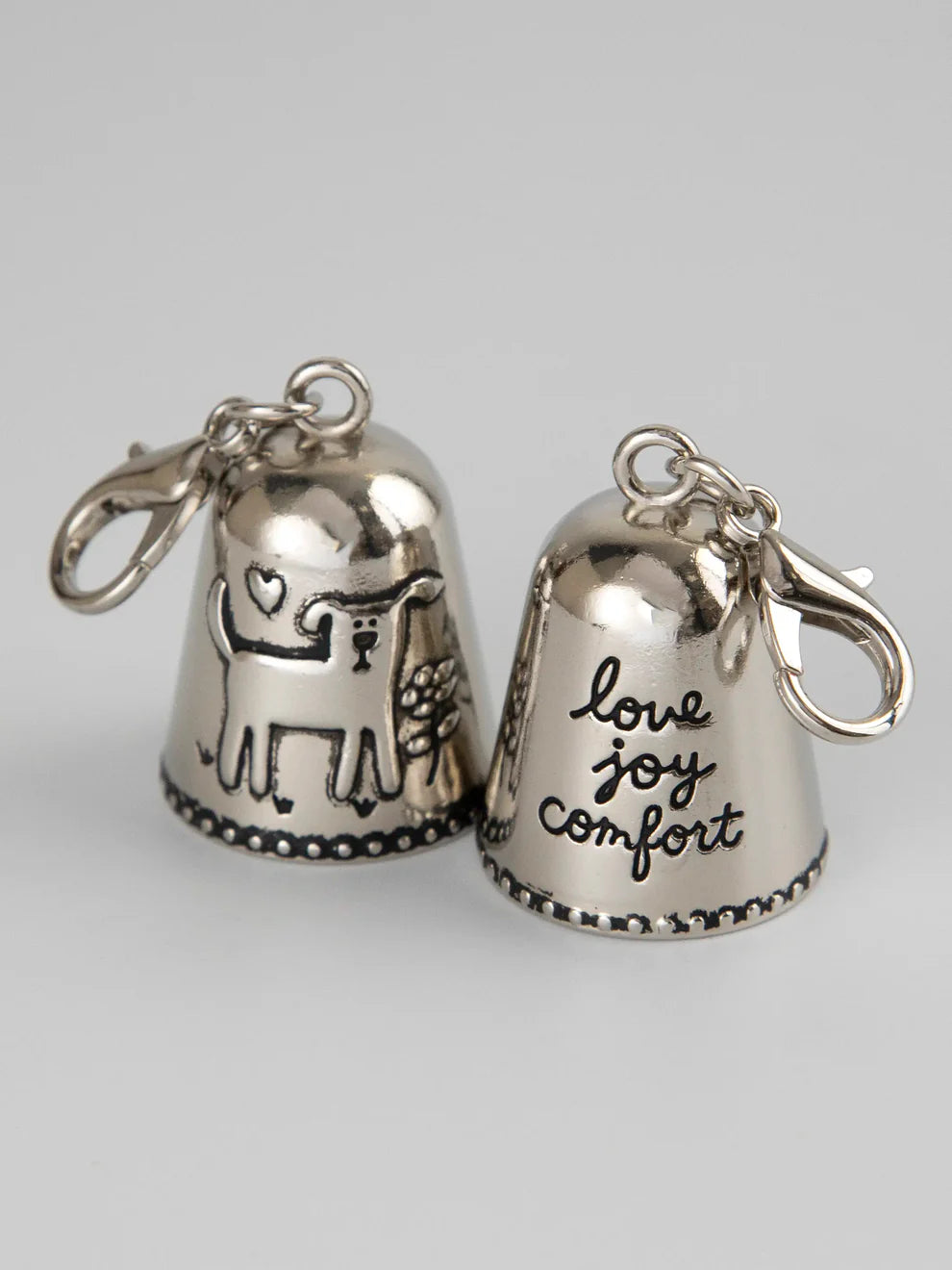 Two silver bells with engraved text on a light gray background