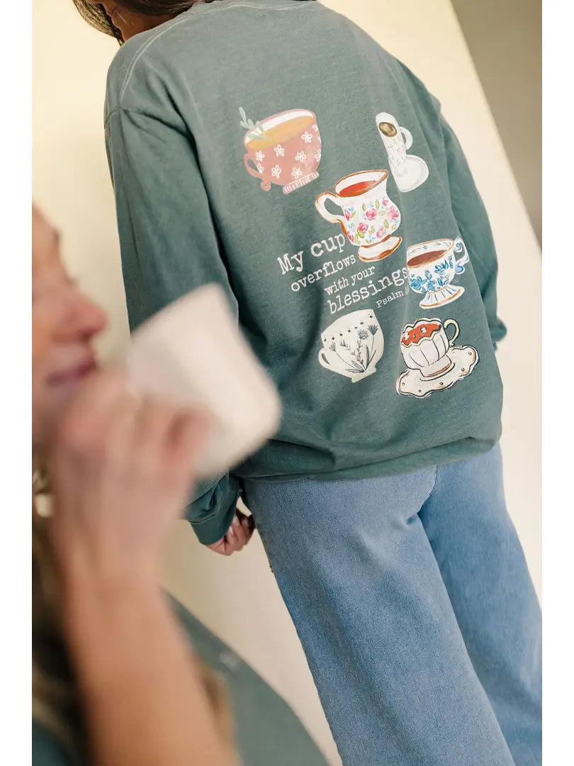 Person wearing a green tshirt with colorful teacup designs and text on the back.