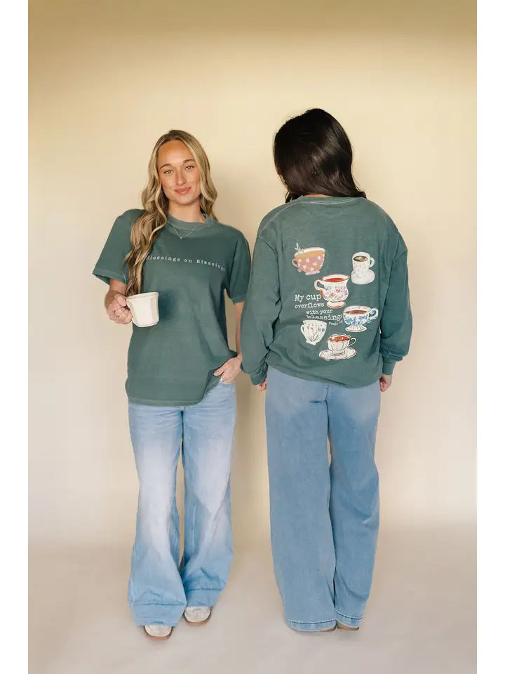Two people wearing green t-shirts with coffee-themed designs on a plain background