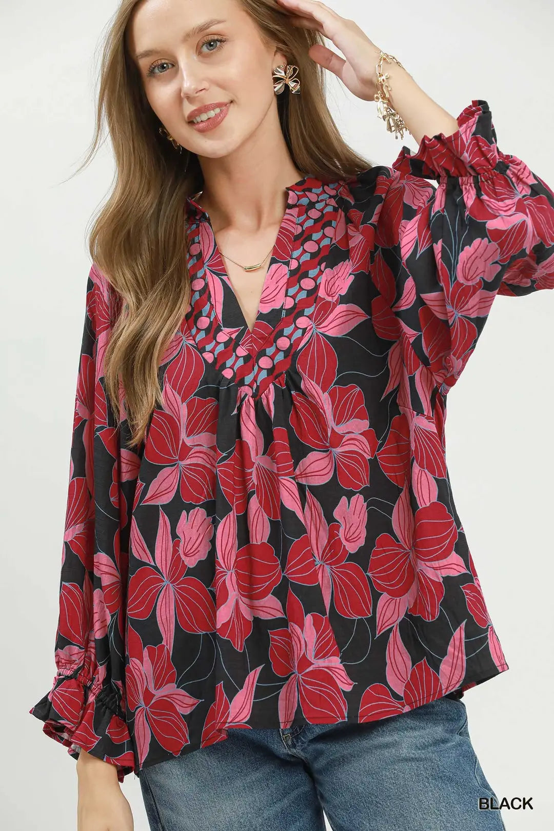 Woman wearing a floral blouse with red and pink patterns on a white background