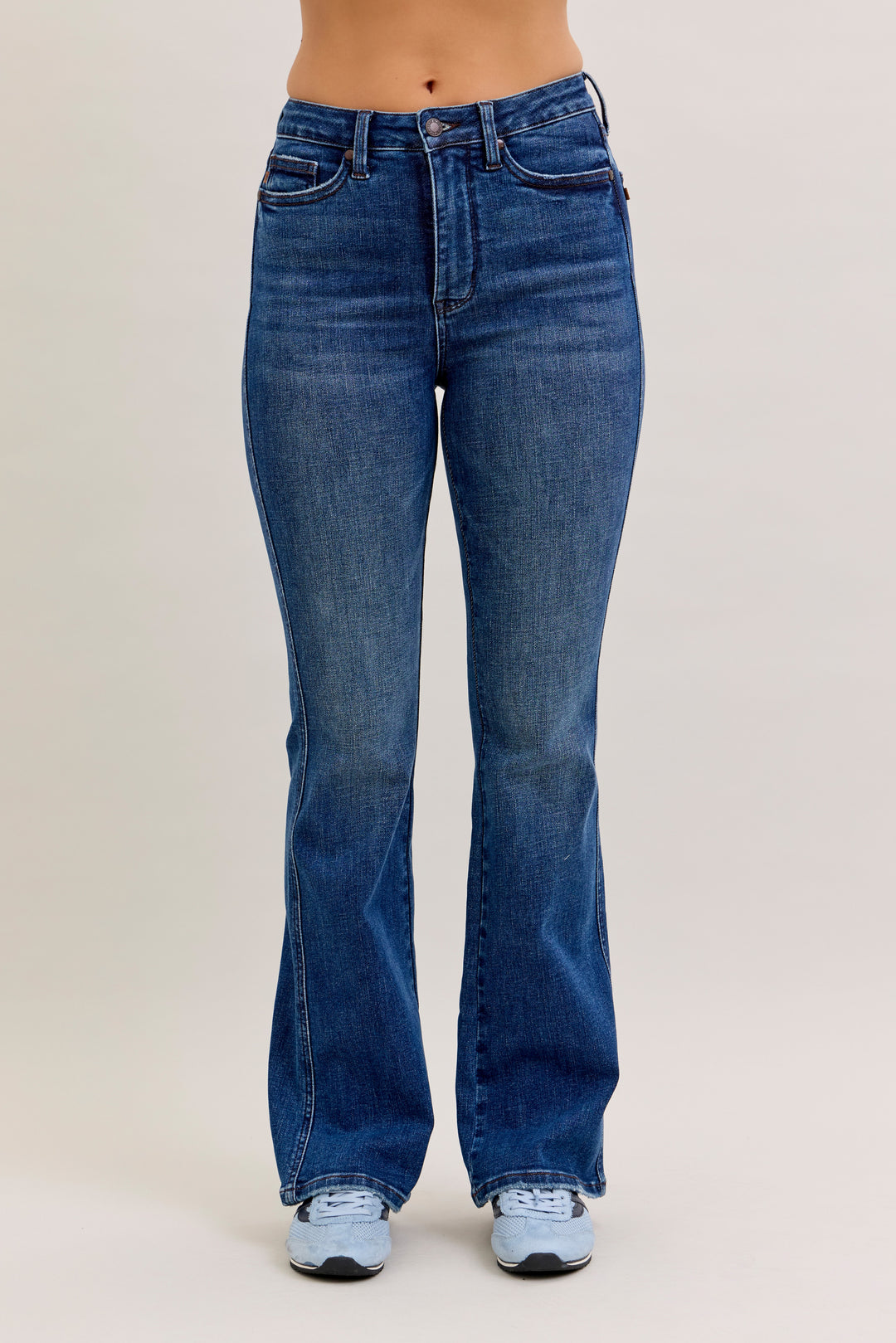 Blue jeans worn by a person on a plain background