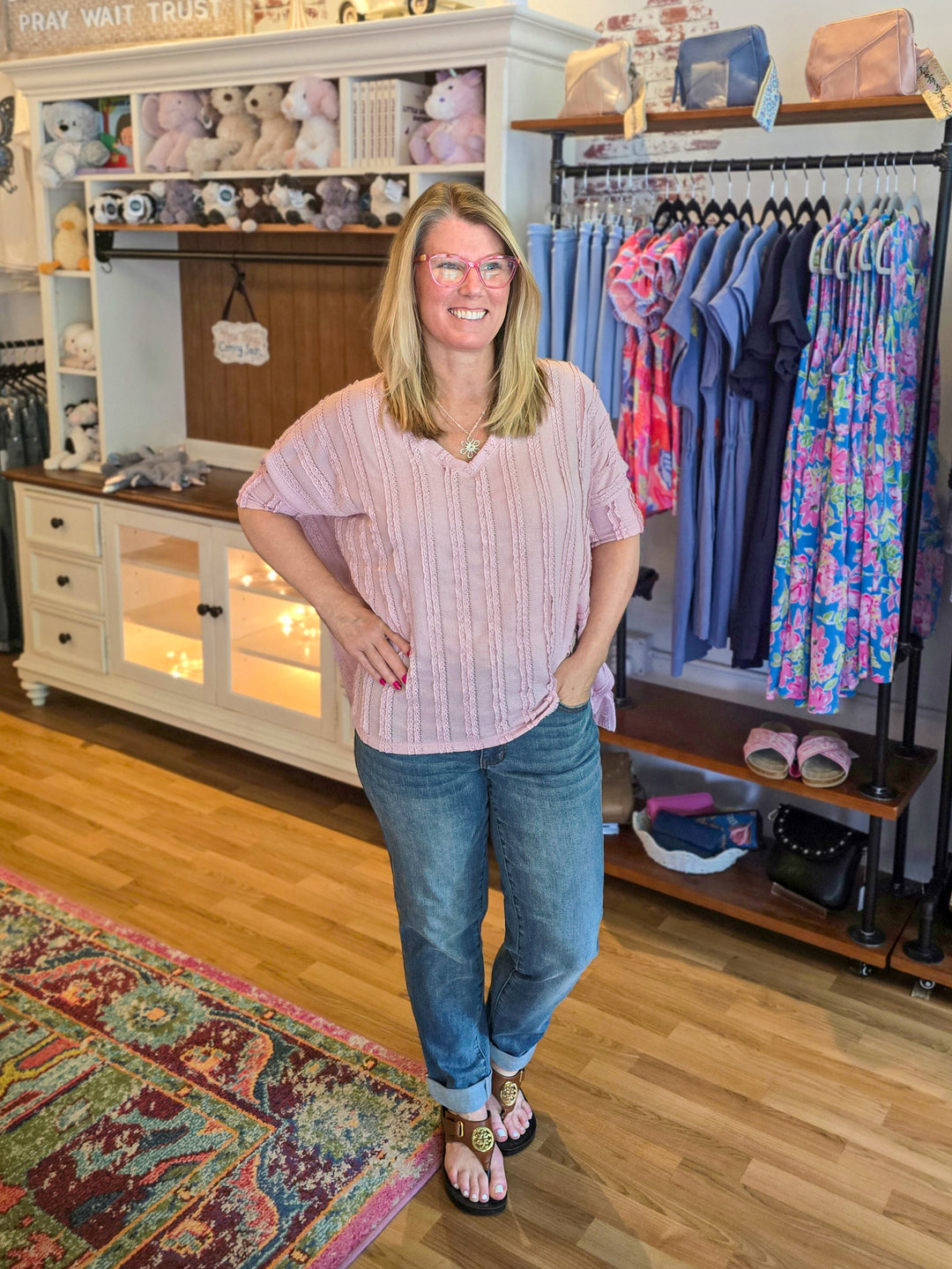 Woman standing in a store with clothing racks and displays in the background