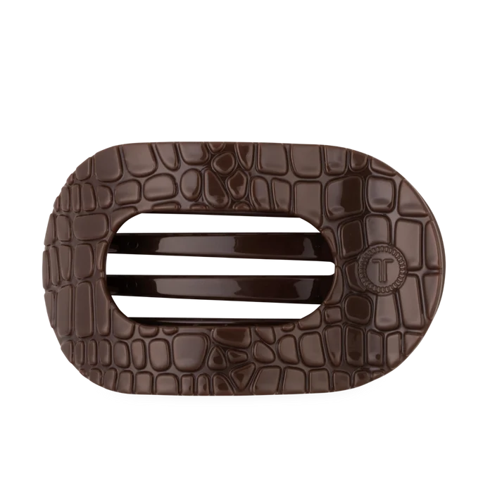 A dark brown textured belt buckle with a crocodile pattern and a central horizontal slot, featuring a circular &