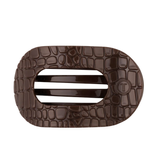 A dark brown textured belt buckle with a crocodile pattern and a central horizontal slot, featuring a circular 'T' logo on the right side, shown on a plain white background.
