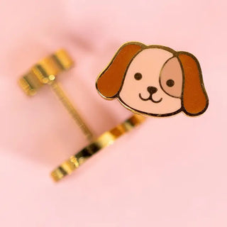 Dog-shaped earrings with gold accents on a pink background