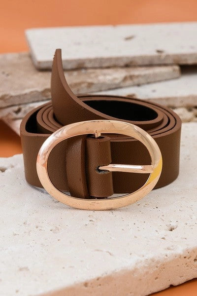 Brown leather belt with a gold buckle on a textured surface