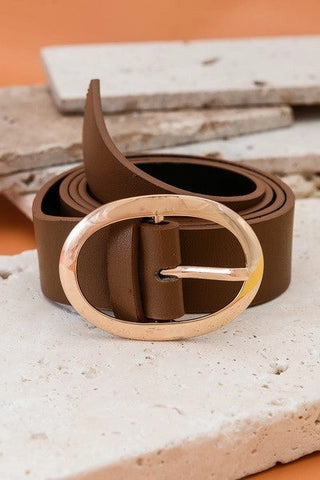 Brown leather belt with a gold buckle on a textured surface