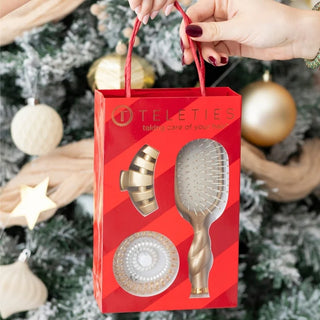 red box with gold hair brush, gold hair clip, and 3 coil hair ties in white and gold. 