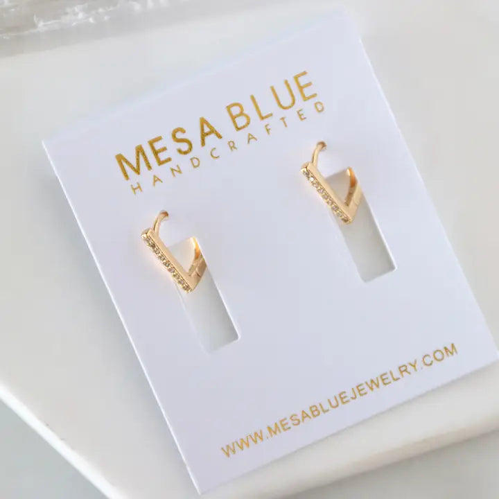 Gold earrings on a Mesa Blue branded card with website information.