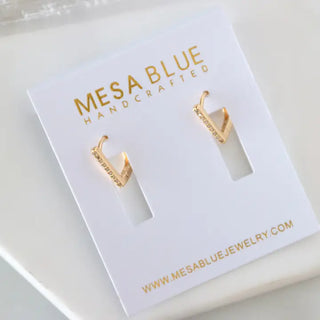 Gold earrings on a Mesa Blue branded card with website information.